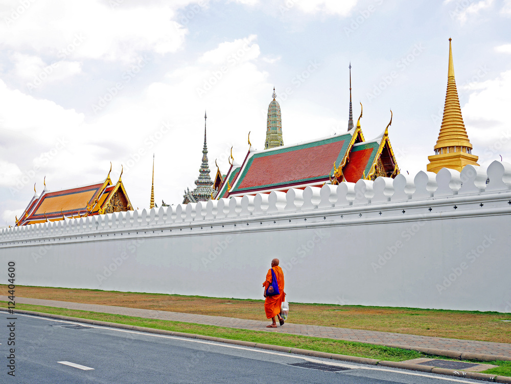 Naklejka premium Monk walking pass Royal palace's wall, Thailand
