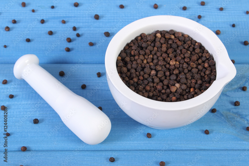 Black pepper in white mortar on blue boards Black pepper in white mortar on blue boards