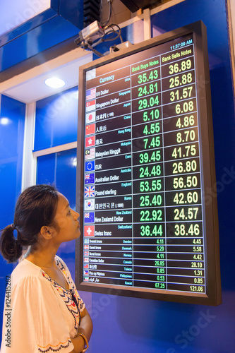 Woman watching the current rate money on board exchange office photo