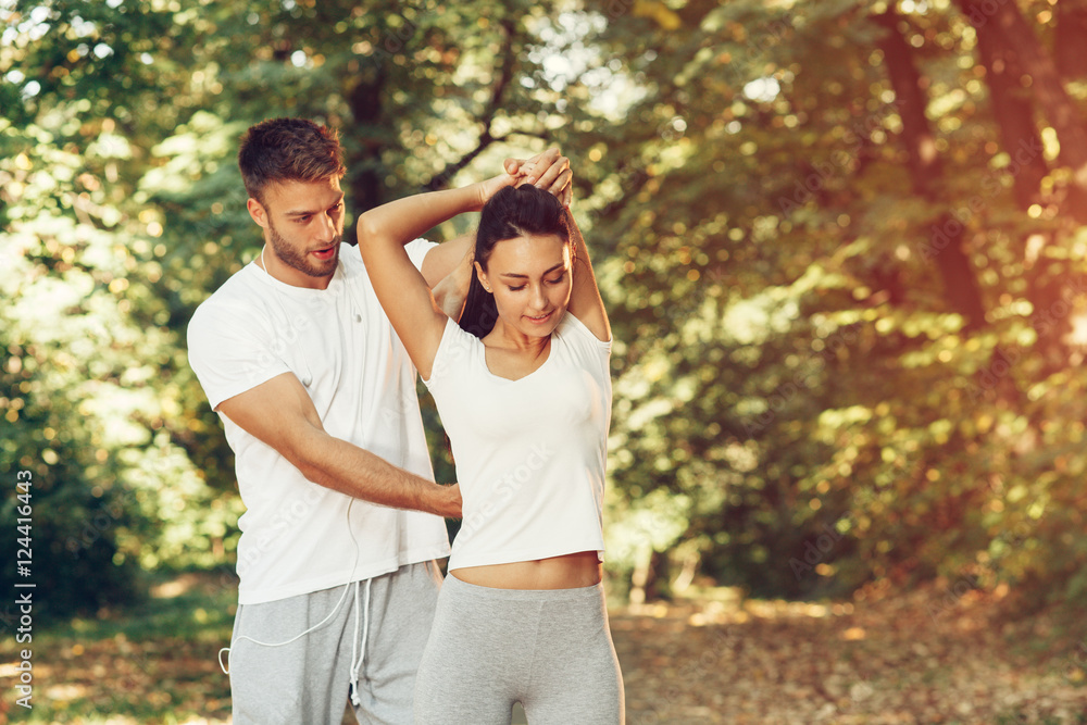 Fototapeta premium Man assisting woman while stretching hands in the park