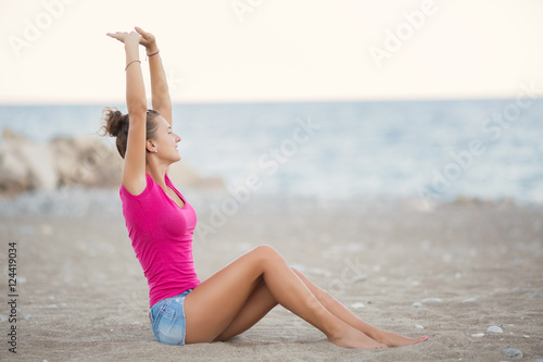 Carefree young woman on sandy beach meditation