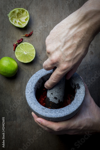 Man's hand with mortar and pestle preparing seasoning paste. Top