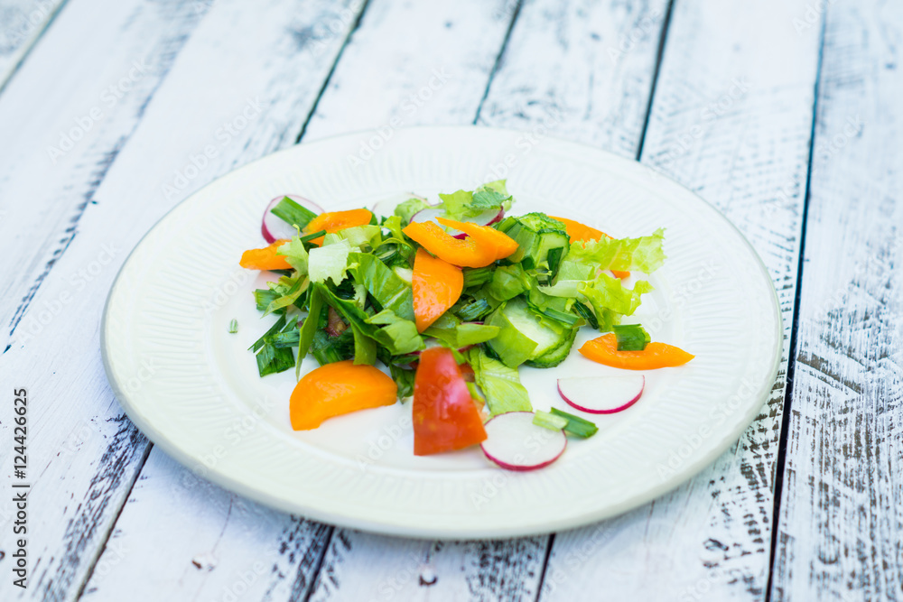 Fresh salad with summer vegetables on the wooden table. Shallow depth of field. Fresh salad with summer vegetables on the wooden table. Shallow depth of field.