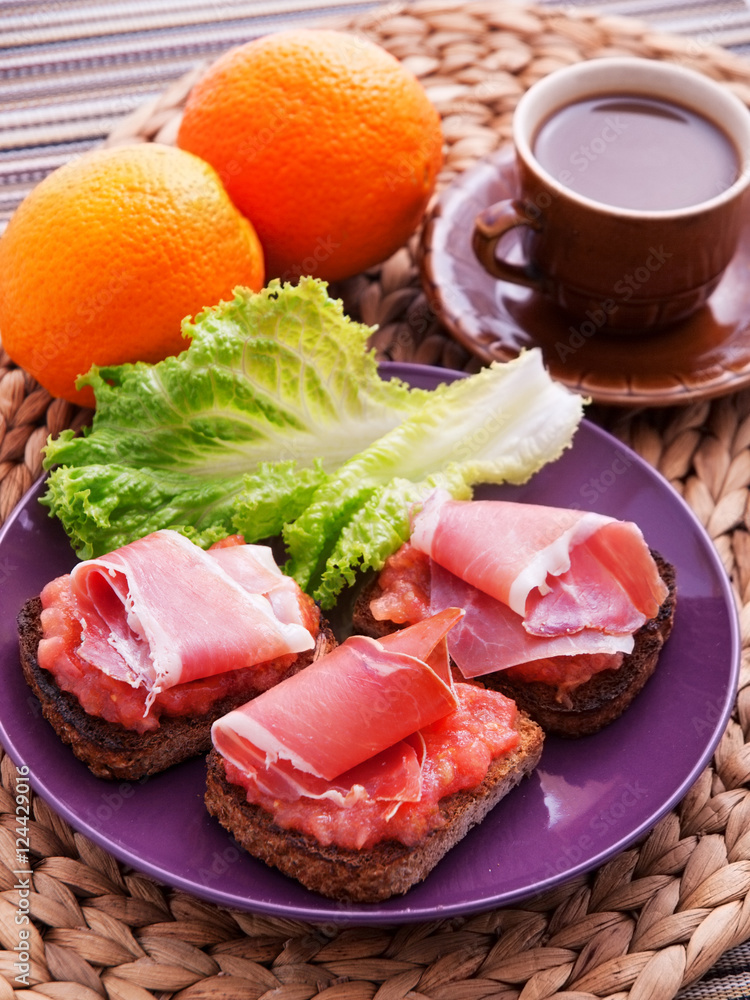 Toasts with prosciutto and tomatoes salsa. Decorated with cup of