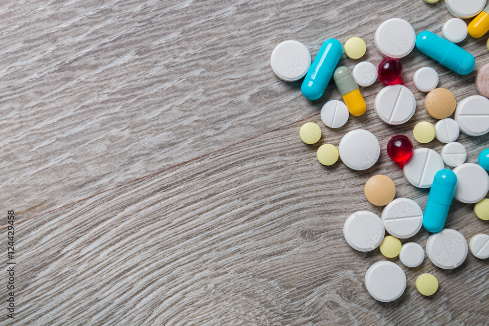 lot of colorful medication and pills from above on grey wooden background. Copy space. Top view, frame. Painkillers, tablets, generic , drugs. lot of colorful medication and pills from above on grey wooden background. Copy space. Top view, frame. Painkillers, tablets, generic , drugs.