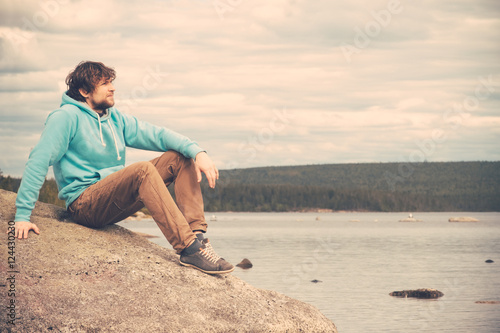 Young Man Traveler relaxing alone outdoor Lifestyle concept with mountains and lake on background