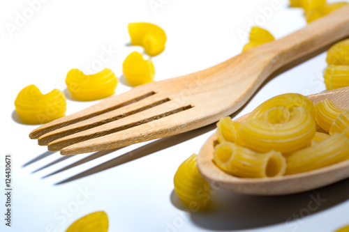 pasta in wooden spoons over white background.