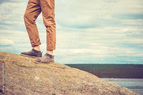 Feet man standing on rocky mountain outdoor Travel Lifestyle vacations concept with sky clouds on background retro colors