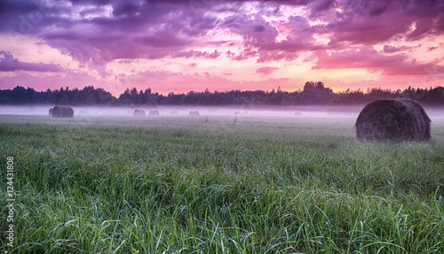 Obraz na plátně Red Sunset on the foggy field with haystacks