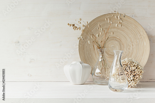 Soft home decor of  glass vase with spikelets and wooden plate on white wood background. Interior. photo