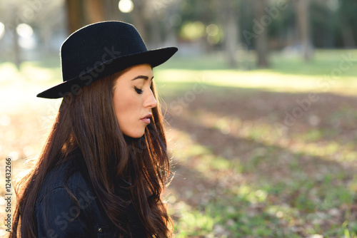 Thoughtful woman sitting alone outdoors wearing hat © javiindy