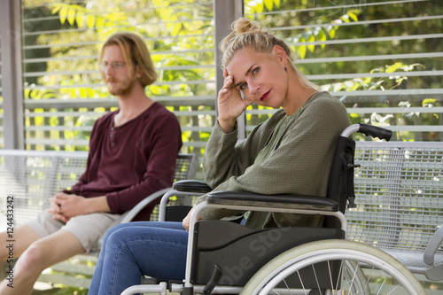woman in wheelchair and young man sitting on bench © wernerimages