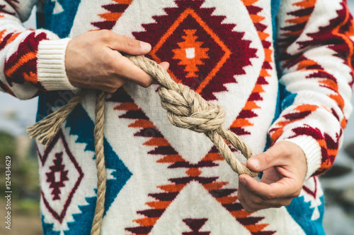 Man hands holding rope knot Travel Lifestyle survival concept wearing knitted sweater outdoor foggy nature on background