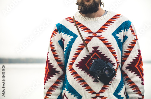 Young Man bearded with retro photo camera Fashion Travel Lifestyle wearing knitted sweater clothing outdoor foggy nature on background