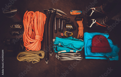 Obraz na płótnie Climbing equipment set: orange rope, crampons, ice axe, shoes, harness and other
