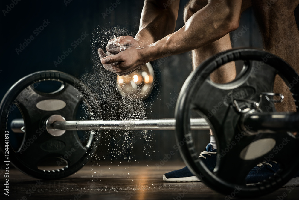 Sports background. Young athlete getting ready for weight lifting training. Powerlifter hand in talc preparing to bench press