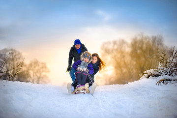 family rides the sledge in the wood