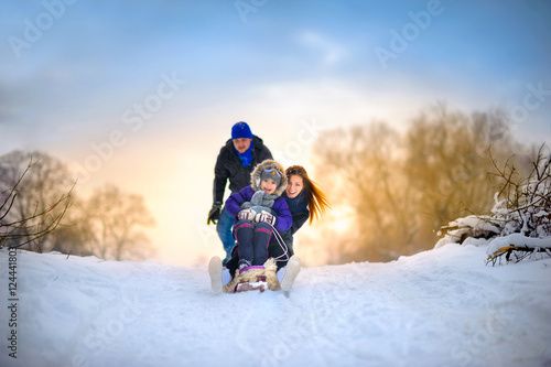 family rides the sledge in the wood