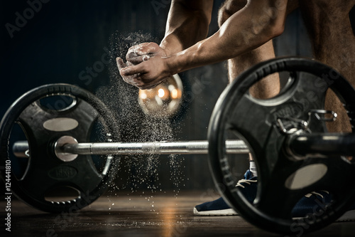 Sports background. Young athlete getting ready for weight lifting training. Powerlifter hand in talc preparing to bench press