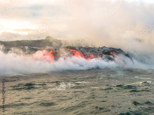 Scenic view from boat in the sunrise of Kilauea Volcano in Hawaii Volcanoes National Park, while erupting lava into Pacific Ocean, Big Island, Hawaii.