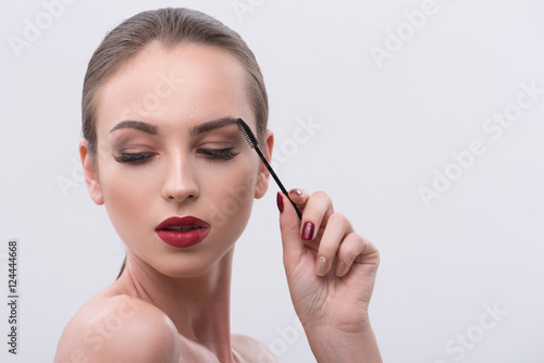 Sensual girl combing her brows carefully