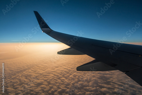 The wing of the airplane above the clouds at sunset.