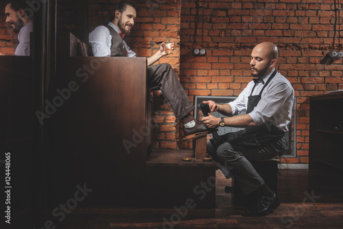 cheerful man resting in front of shoeshiner indoors