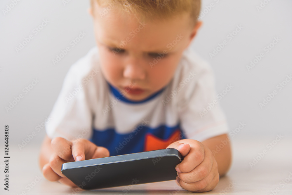 Little boy sitting with digital gadgets in studio Little boy sitting with digital gadgets in studio