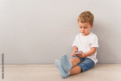 Little boy sitting with smartphone in studio