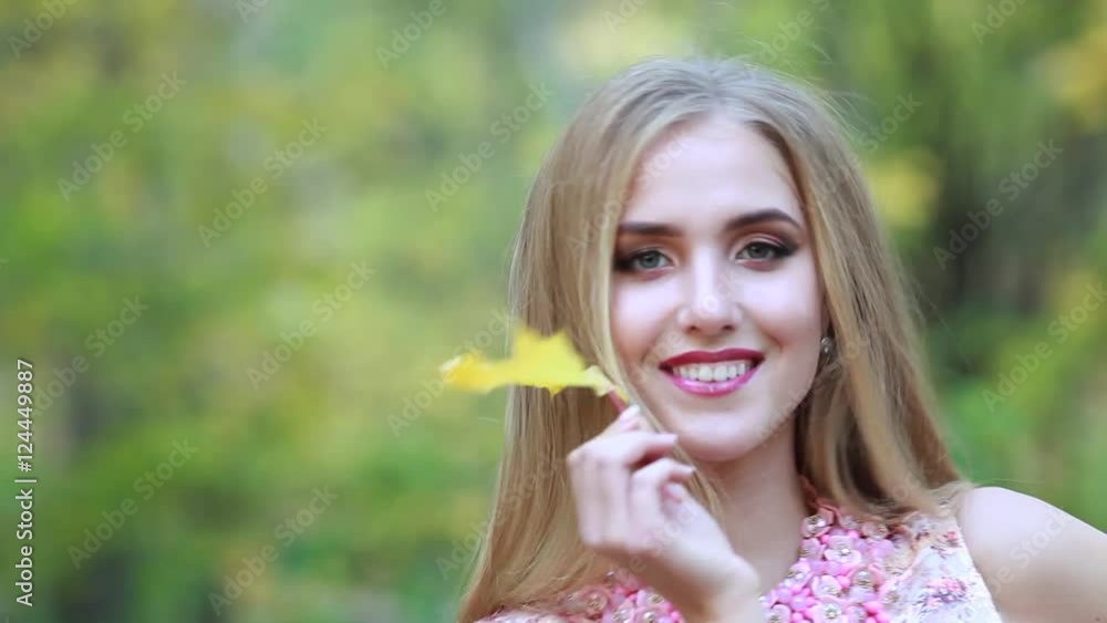 Beautiful woman covers her face with yellow maple leaves in autumn day in the park Beautiful woman covers her face with yellow maple leaves in autumn day in the park