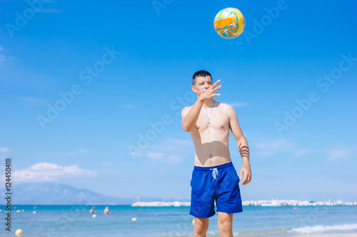 young man with volleyball playing volley on the beach