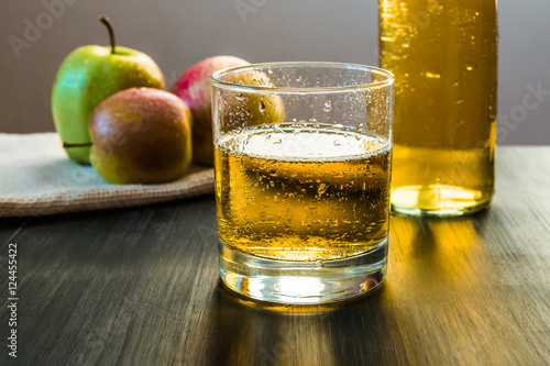 apple wine in a glass in front of apples on wooden rustic table