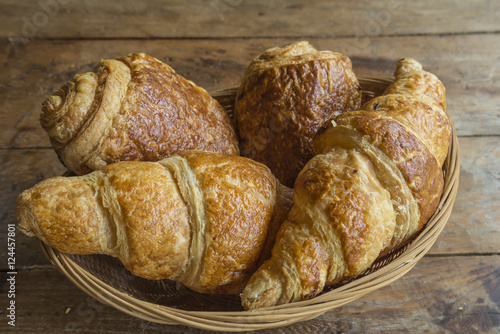 Hot croissants in basket on old wooden table