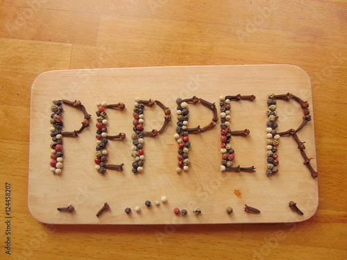 Pepper written on cutting board with pepper  photo