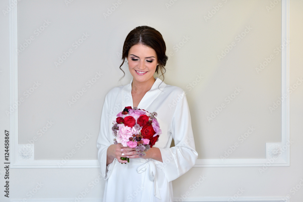 Beauty bride in dressing gown with bouquet indoors. Beautiful model girl in colorful wedding robe. Female portrait of cute lady. Woman with hairstyle Beauty bride in dressing gown with bouquet indoors. Beautiful model girl in colorful wedding robe. Female portrait of cute lady. Woman with hairstyle