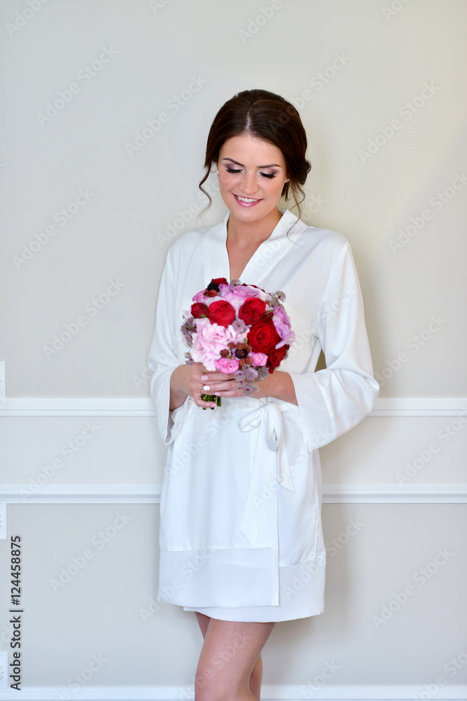 Beauty bride in dressing gown with bouquet indoors. Beautiful model girl in colorful wedding robe. Female portrait of cute lady. Woman with hairstyle Beauty bride in dressing gown with bouquet indoors. Beautiful model girl in colorful wedding robe. Female portrait of cute lady. Woman with hairstyle