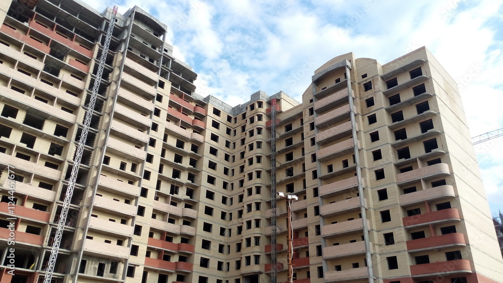 Under construction high-rise brick building on blue sky background