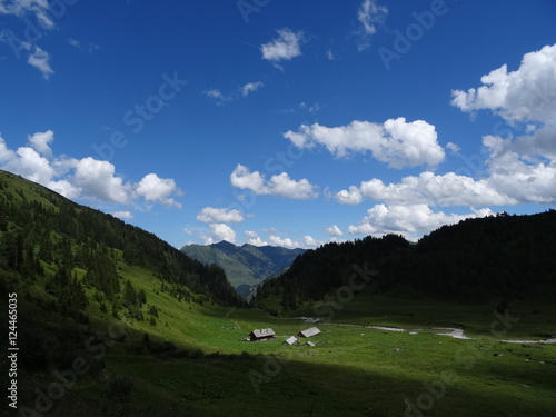 Urlaub in den Bergen, die Hirzbachalm, mit Alm, Wiese, Bergwald, Berge und ziehende Wolken am blauen Himmel photo