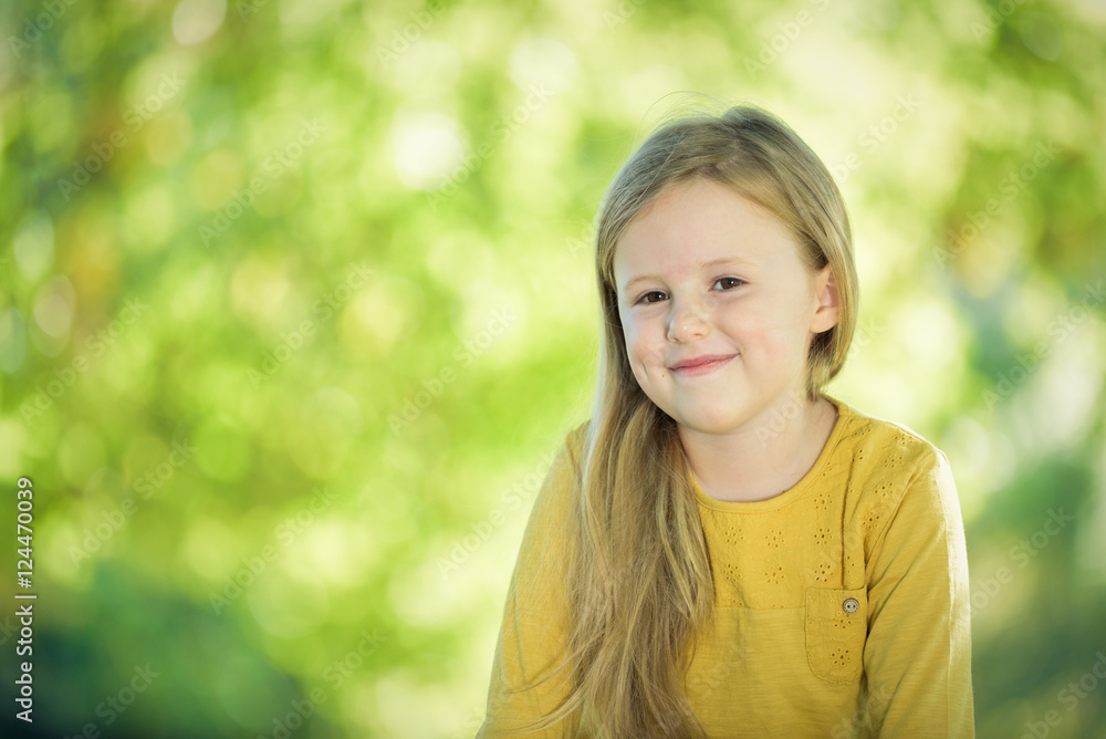 Sympathetic and beautiful little girl on a bench in a park in th Sympathetic and beautiful little girl on a bench in a park in th