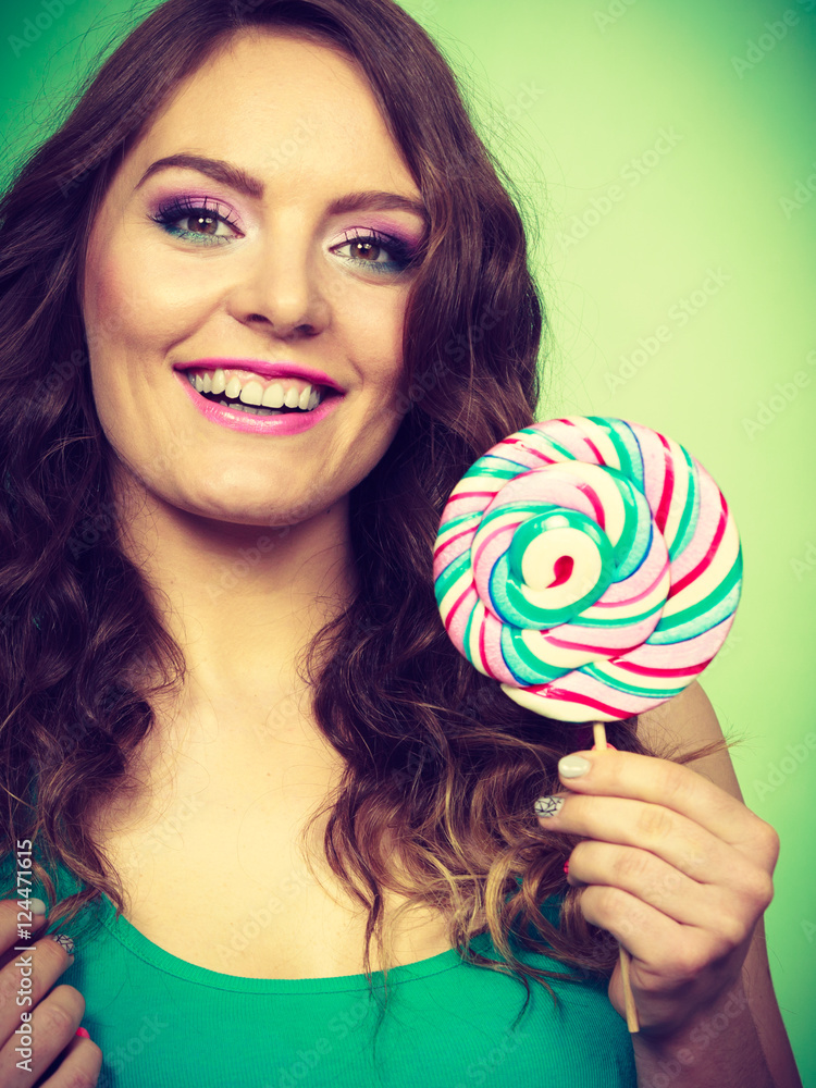 Smiling girl with lollipop candy on green