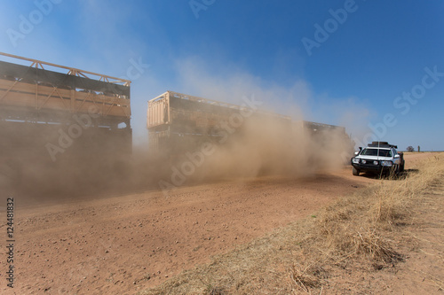Double deck cattle road train passing a 4WD  on dusty outback ro