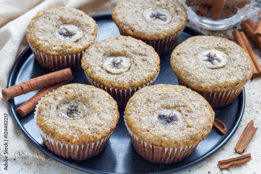 Freshly baked homemade banana cinnamon muffins with slice of banana on top, on the tray Freshly baked homemade banana cinnamon muffins with slice of banana on top, on the tray