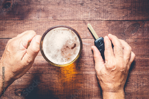 Man hand drinking beer and holding car keys photo