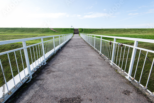 Diminishing perspective of metal suspension footbridge over rive