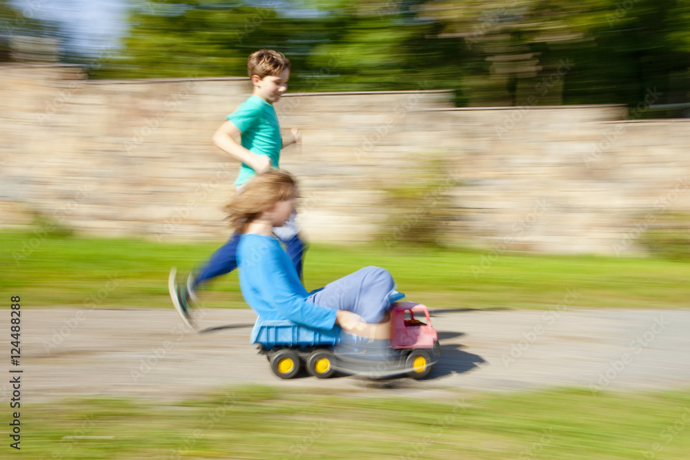 Two Boys Riding Downhill on Top of Toy Lorry