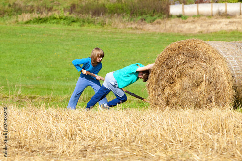 Two Boys Moving Bale of Hay with Stick as a Lever