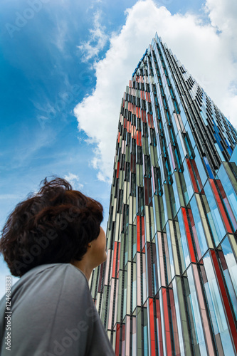 tourist looks at modern skyscraper against blue sky