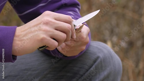 Process of planing piece of wood / Hands of young man whittling piece of wood using pocket knife