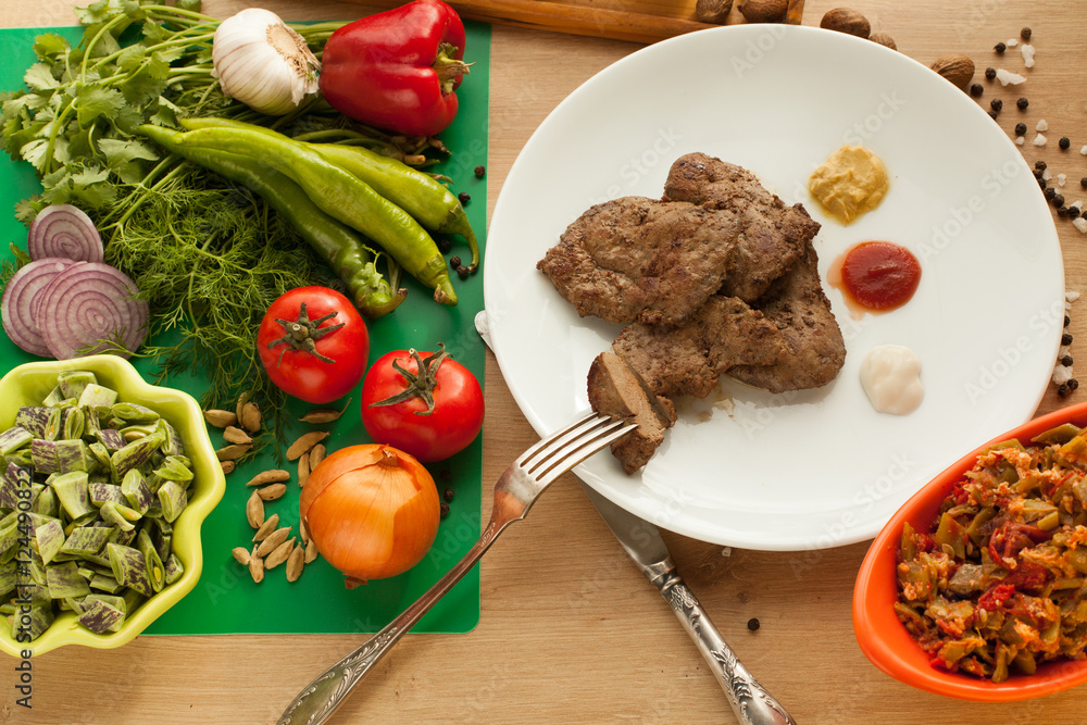 Roast meat served with ketchup, mayonnaise and mustard, sliced piece of meat hanging on a fork. Cooked liver with spices. Vegetarian food against meat. Vegetables vs meat. Roast meat served with ketchup, mayonnaise and mustard, sliced piece of meat hanging on a fork. Cooked liver with spices. Vegetarian food against meat. Vegetables vs meat.