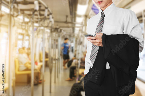Business office employee using smartphone in subway or sky train, going to work in sunrise morning